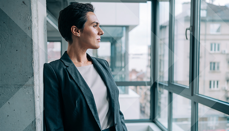 Shot of beautiful businesswoman standing in her office and looking through window.