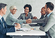 A meeting between five businesspeople of various ethnicities, two of them shaking hands