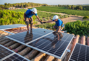 Two workers on a rooftop installing solar panels