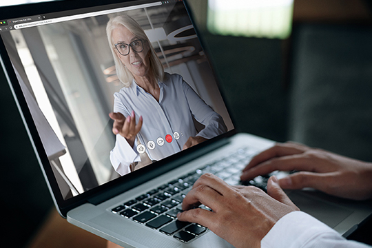 “A businessman speaks on a web conference with an advisor using a laptop webcam”