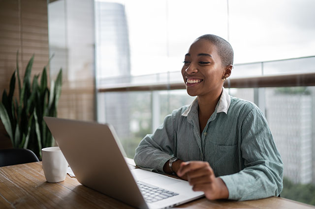 A young black woman working and holding a virtual meeting on her laptop.