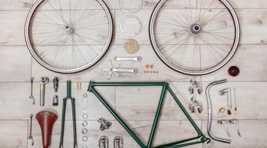 Un cadre de vélo et ses composants posés sur des planches de bois.