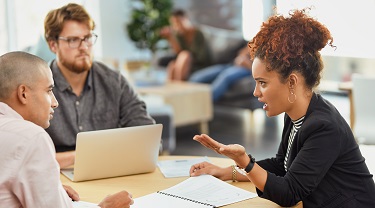 Two males, female colleagues discuss export strategy in office