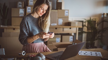 A business woman at work is consulting her mobile phone.