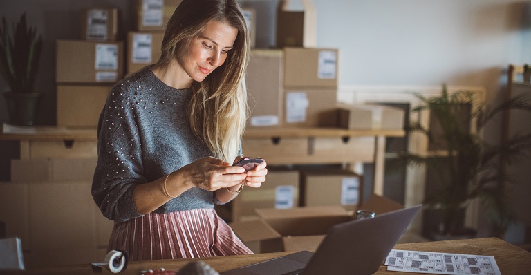 A business woman at work is consulting her mobile phone.