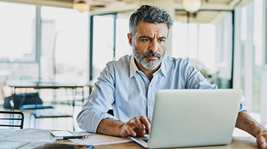 Mature businessman using laptop at a table.