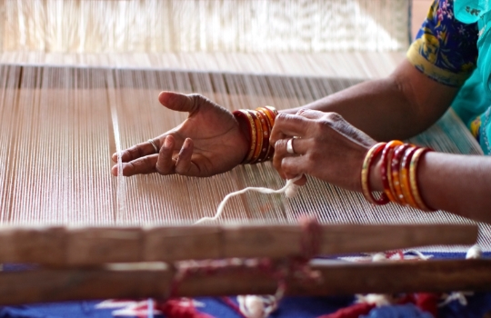 Indian woman weaving by hand on a loom