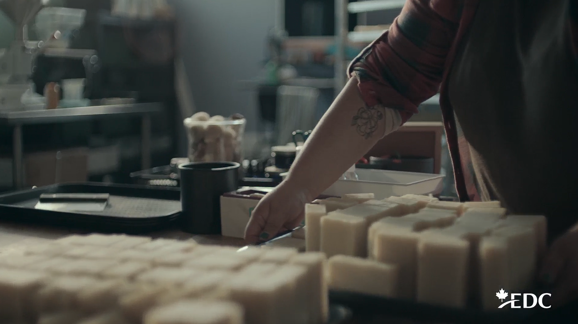 Person arranging handmade soap bars on a worktable in a small workshop