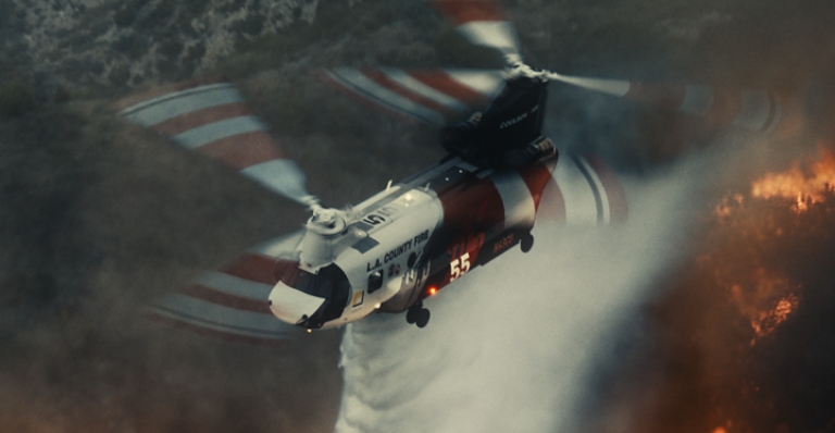 A Coulson Aviation aircraft flying over a raging forest fire below