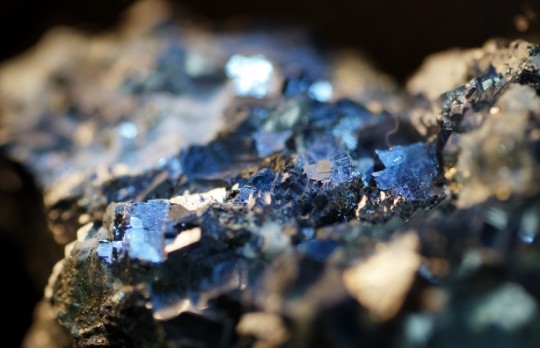 Close-up of mineral formations embedded in rock, with reflective surfaces catching the light