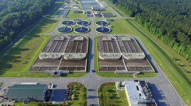 Vue aérienne d'une usine de traitement d'eau entourée d'arbres et d'espaces verts.