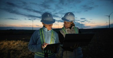 Image of female engineers discussing implementation of wind turbines on farm.