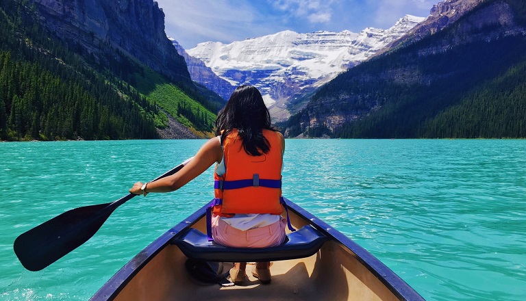 Une femme qui pagaye en canot sur le lac Moraine