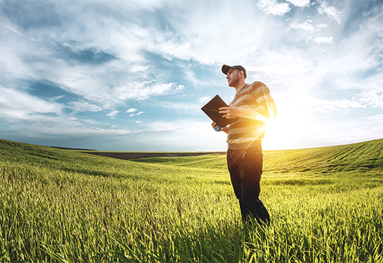 Man standing in green field with a cloudy sky