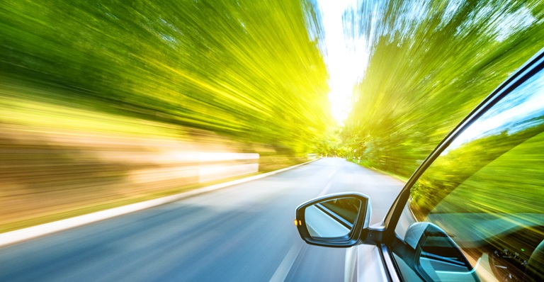 Voiture de course avec des arbres verts floutés de chaque côté.