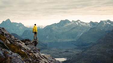 Male hiker stands on precarious mountain ledge