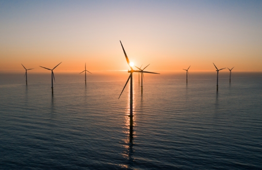 Éoliennes en mer au lever du soleil.