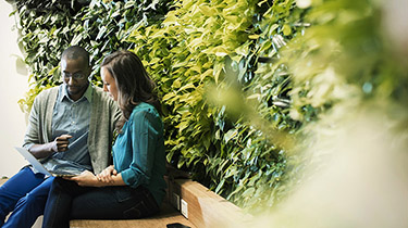 Image of two people on bench with greenery representing strong environment, social and governance practices are at the heart of EDC’s business approach.