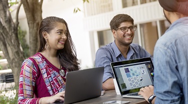 Smiling Canadian-Indian exporters hold meeting outdoors at standup desk