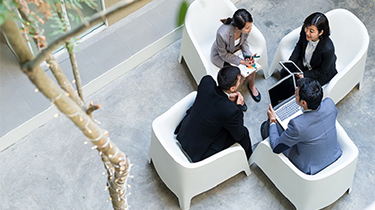 a group of coworkers are sitting in round holding a discussion