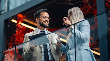 Des collègues discutant du financement des affaires pour les exportateurs sur le balcon d'un bureau.