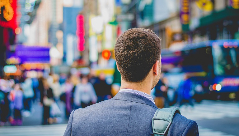 Businessman prepares to cross street in busy downtown