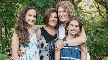 Jennifer Cooke embraces her mother and two young daughters in a lovely garden.