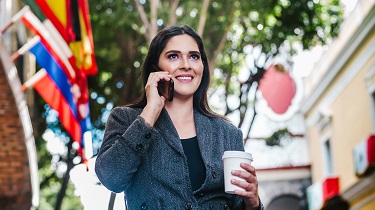 Latin businesswoman in street with international flags overhead.