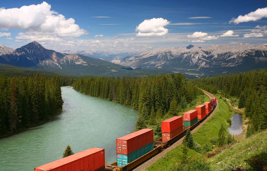 Freight train chugs alongside Bow River in Canadian Rockies