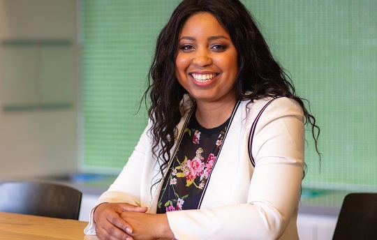 A smiling EDC employee is shown sitting at a table in the EDC Ottawa office.