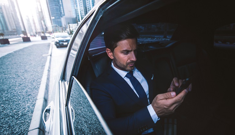 Worried businessman checks phone while driving in a limo