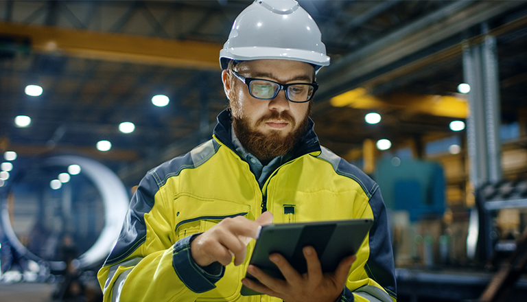 An industrial engineer wearing his hard hat and his security vest is working at the plant.
