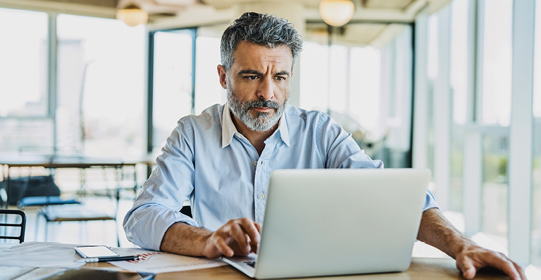 Mature businessman using laptop at a table.